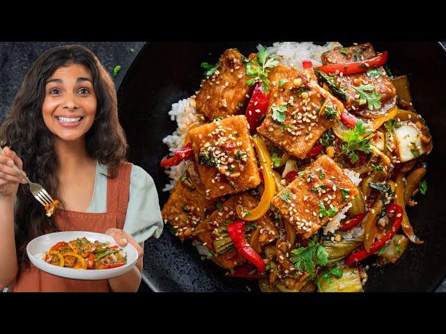 A person enjoying a plate of Luffa Tofu Stir-Fry, smiling