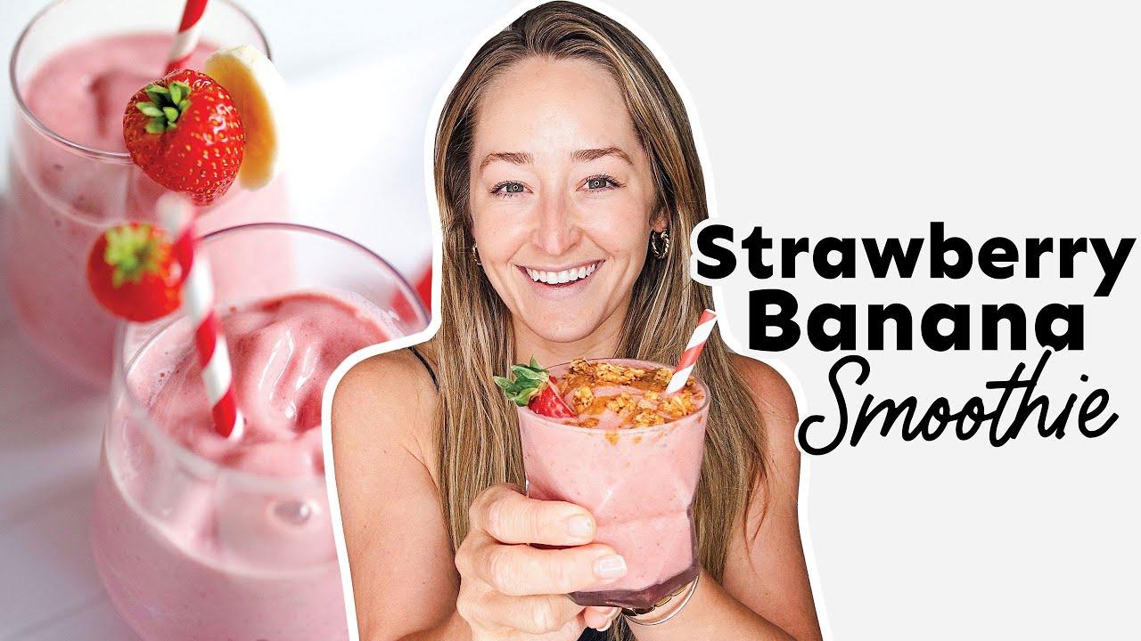 a person smiling while holding a glass of golden strawberry banana smoothie