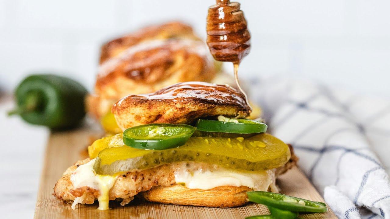 Hot honey fried chicken biscuit sandwich with sweet heat drizzle, golden crispy chicken, fluffy biscuit, natural lighting, garnished with chives.