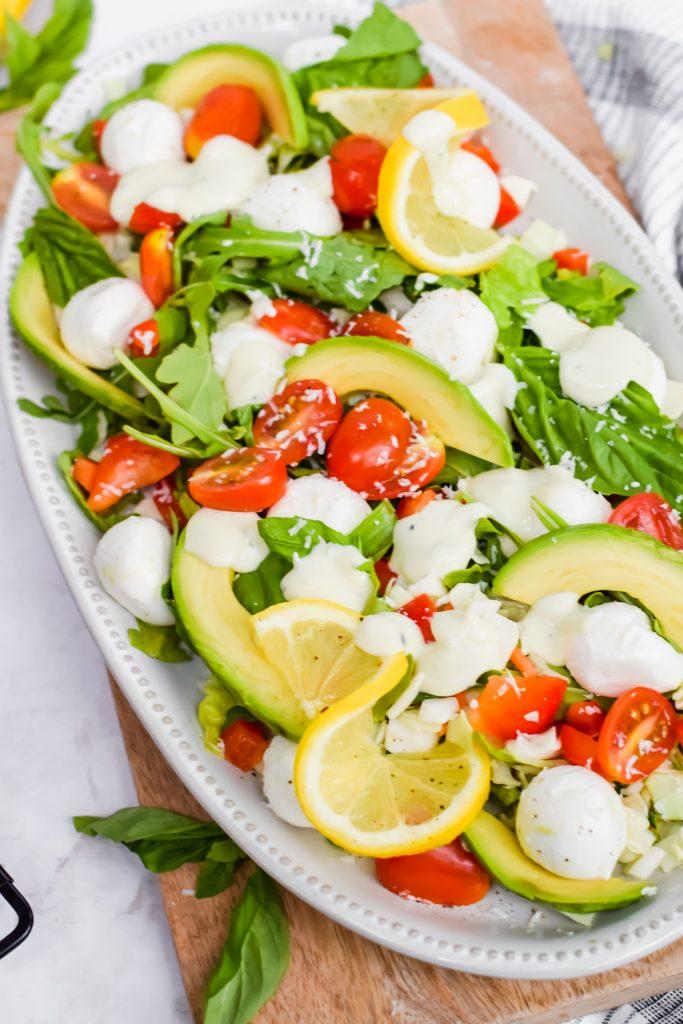 Close-up shot of Caprese salad with arugula and pesto drizzled on top