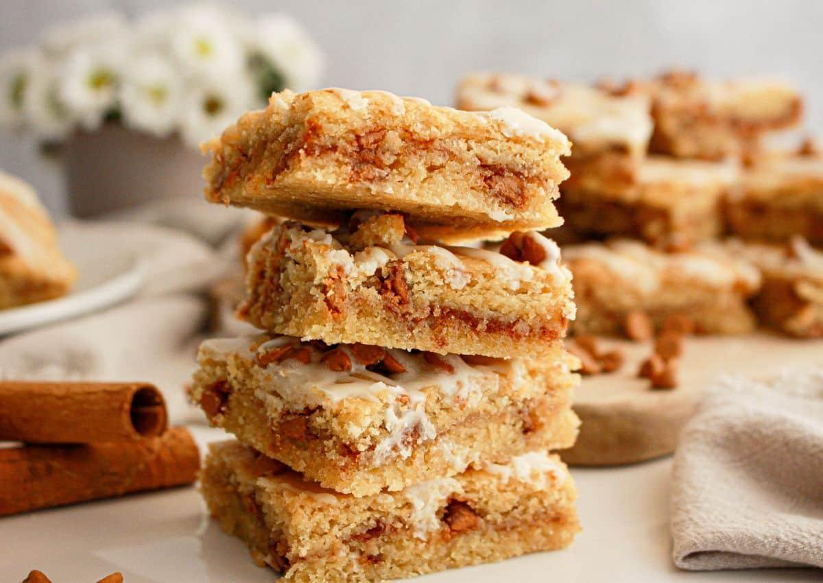 Warm cinnamon cookie squares stacked on a white plate with a sprinkle of powdered sugar