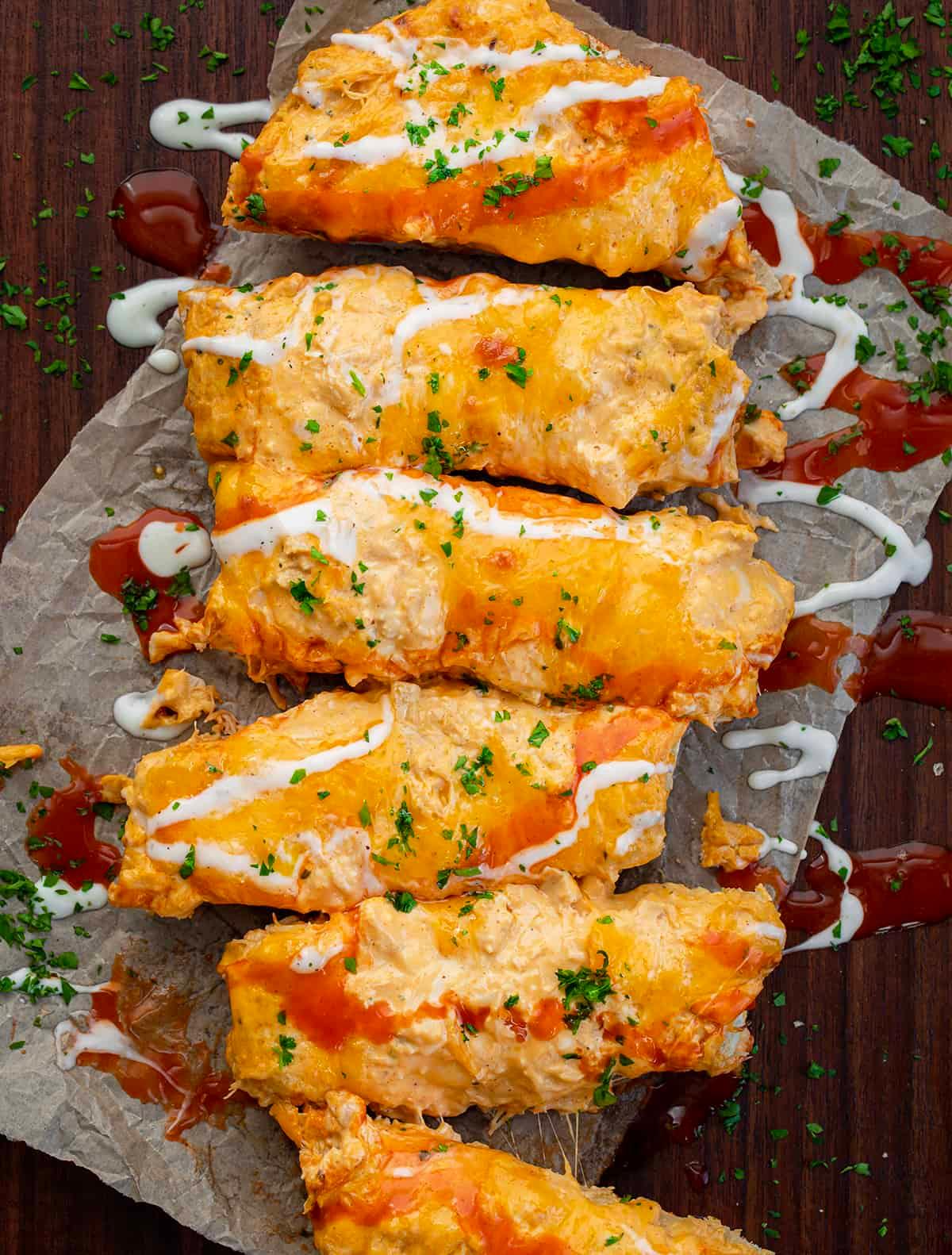 Hands tearing off a piece of buffalo chicken bread from a larger loaf, showing melted cheese and chicken filling.