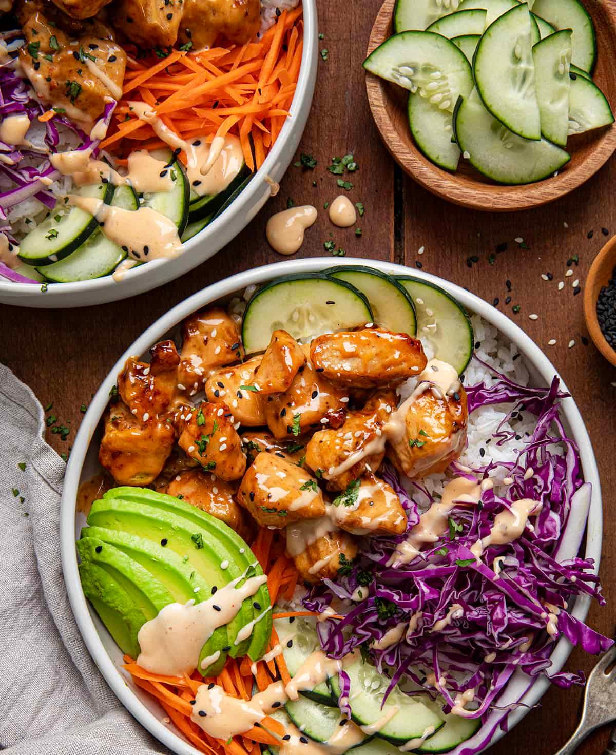 Overhead shot of an assembled Bang Bang Chicken Bowl with rice, chicken, sauce, and garnishes