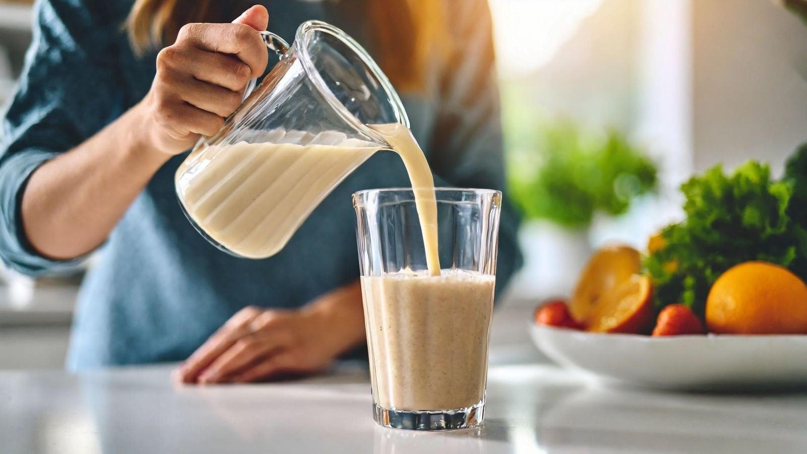 a person pouring a coconut flour protein smoothie into a glass