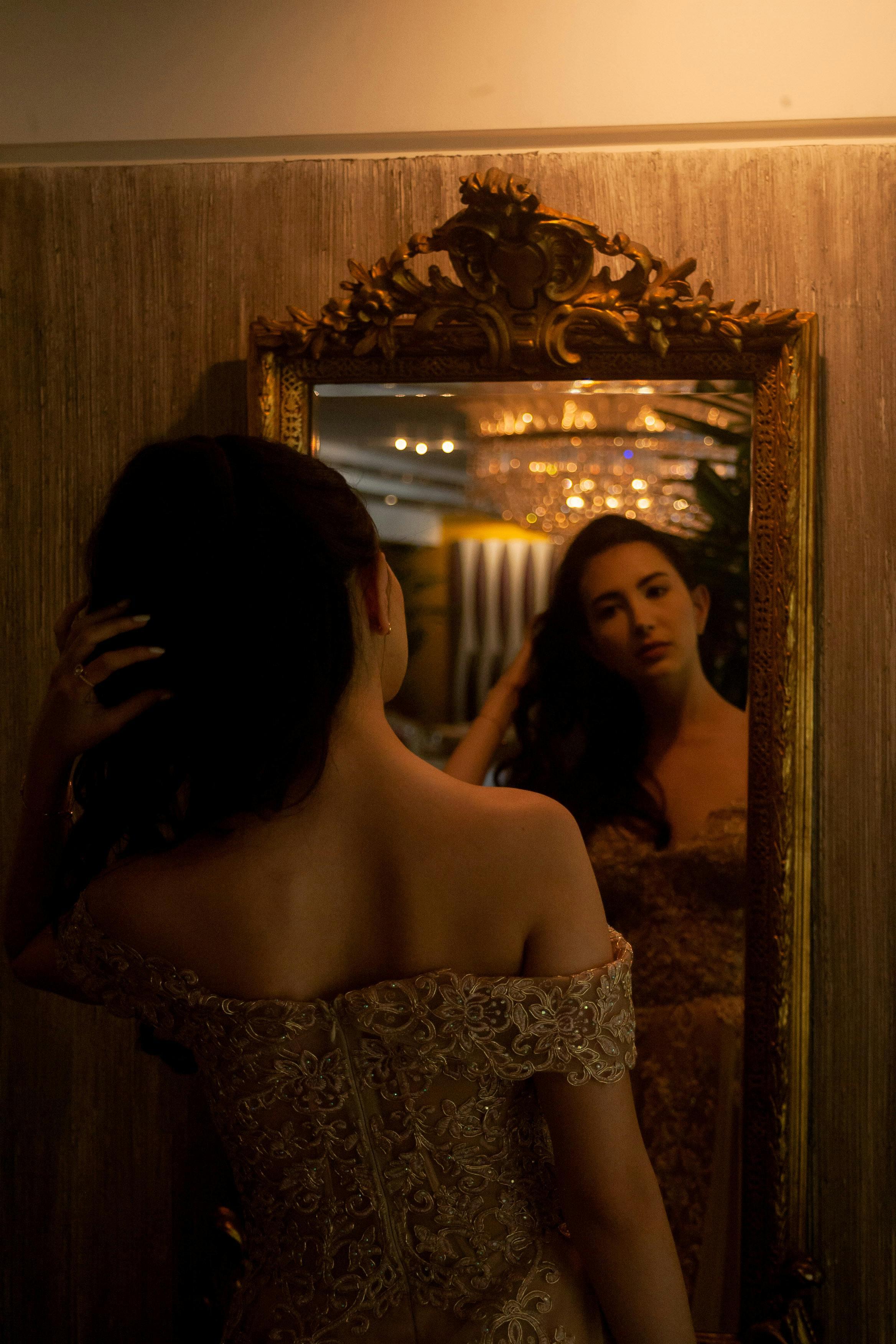Woman trying on graduation dresses, looking at herself in a mirror