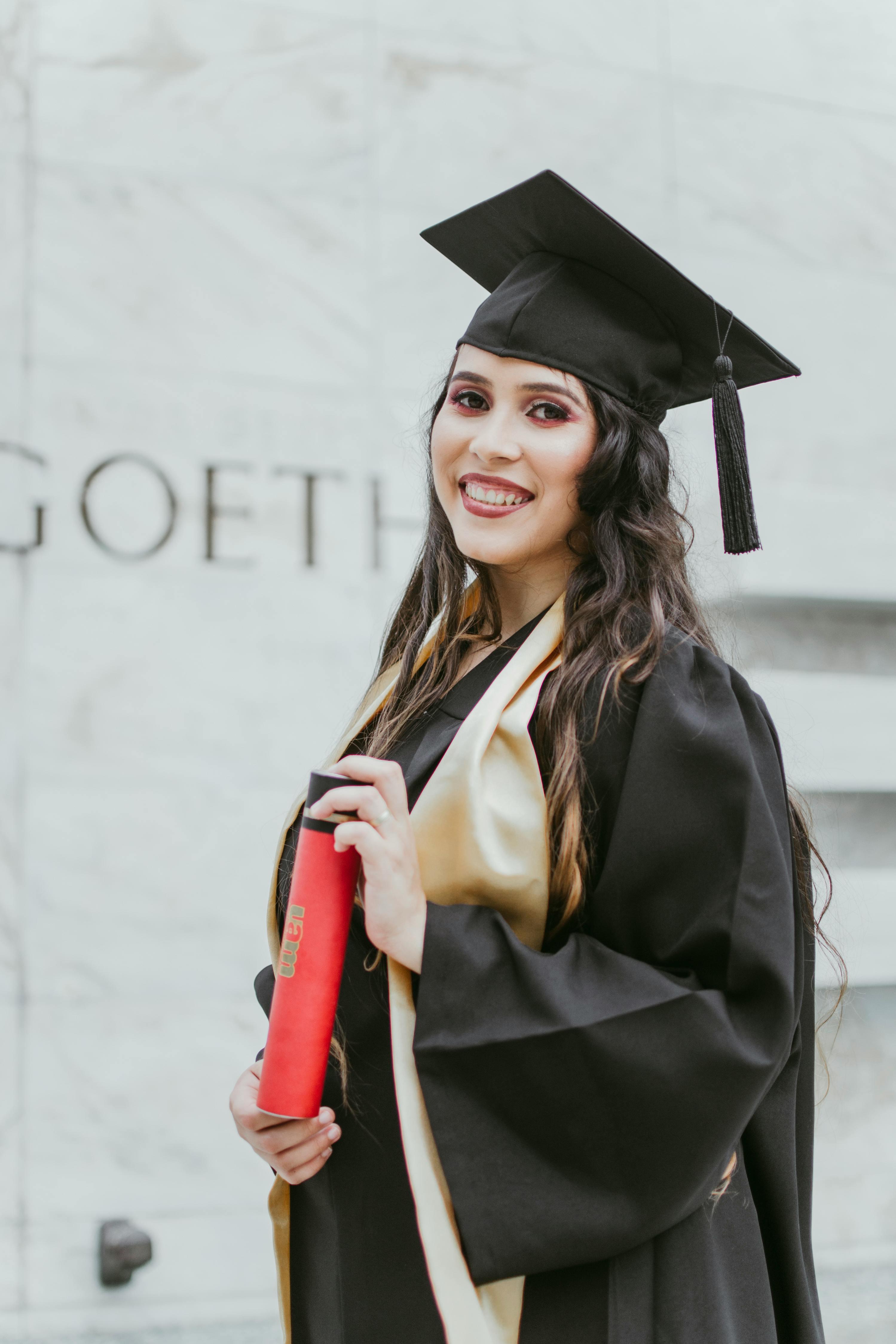 Woman smiling happily and holding a vintage-inspired graduation dress