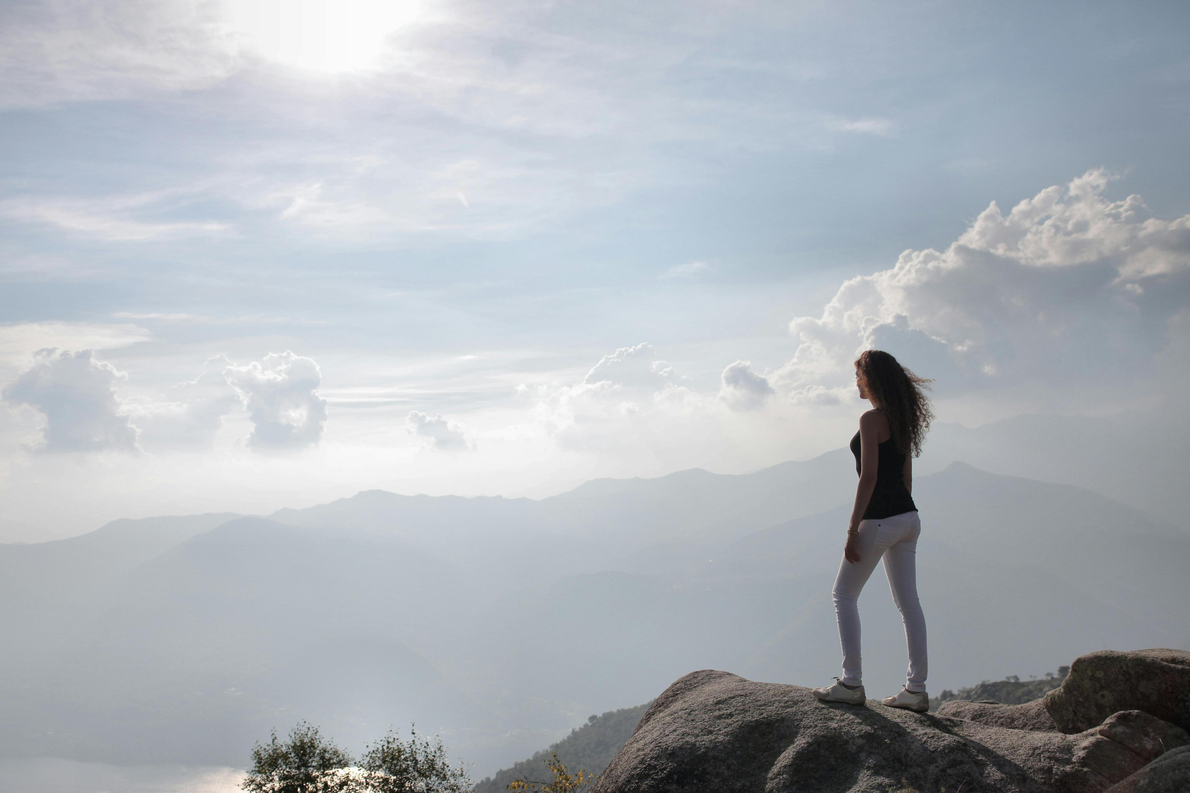 woman standing on a mountaintop looking out at a scenic view