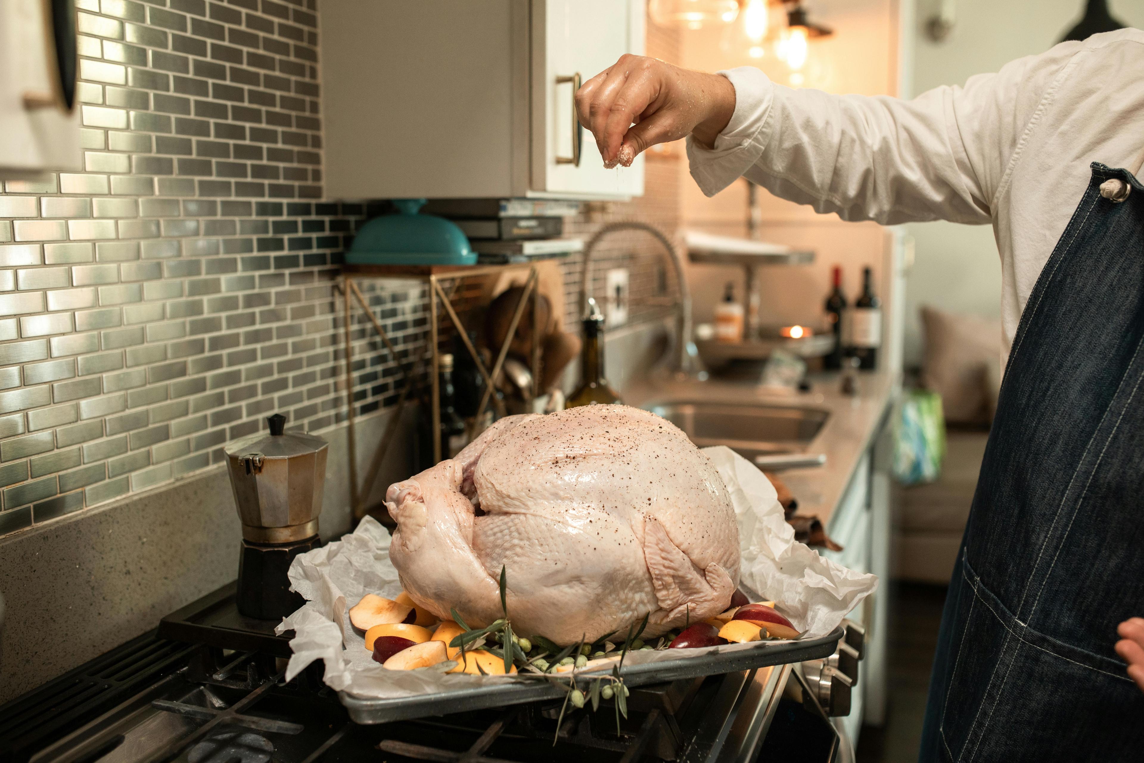 Person carefully patting a raw whole turkey dry with paper towels, a look of focused determination, in a cozy kitchen.
