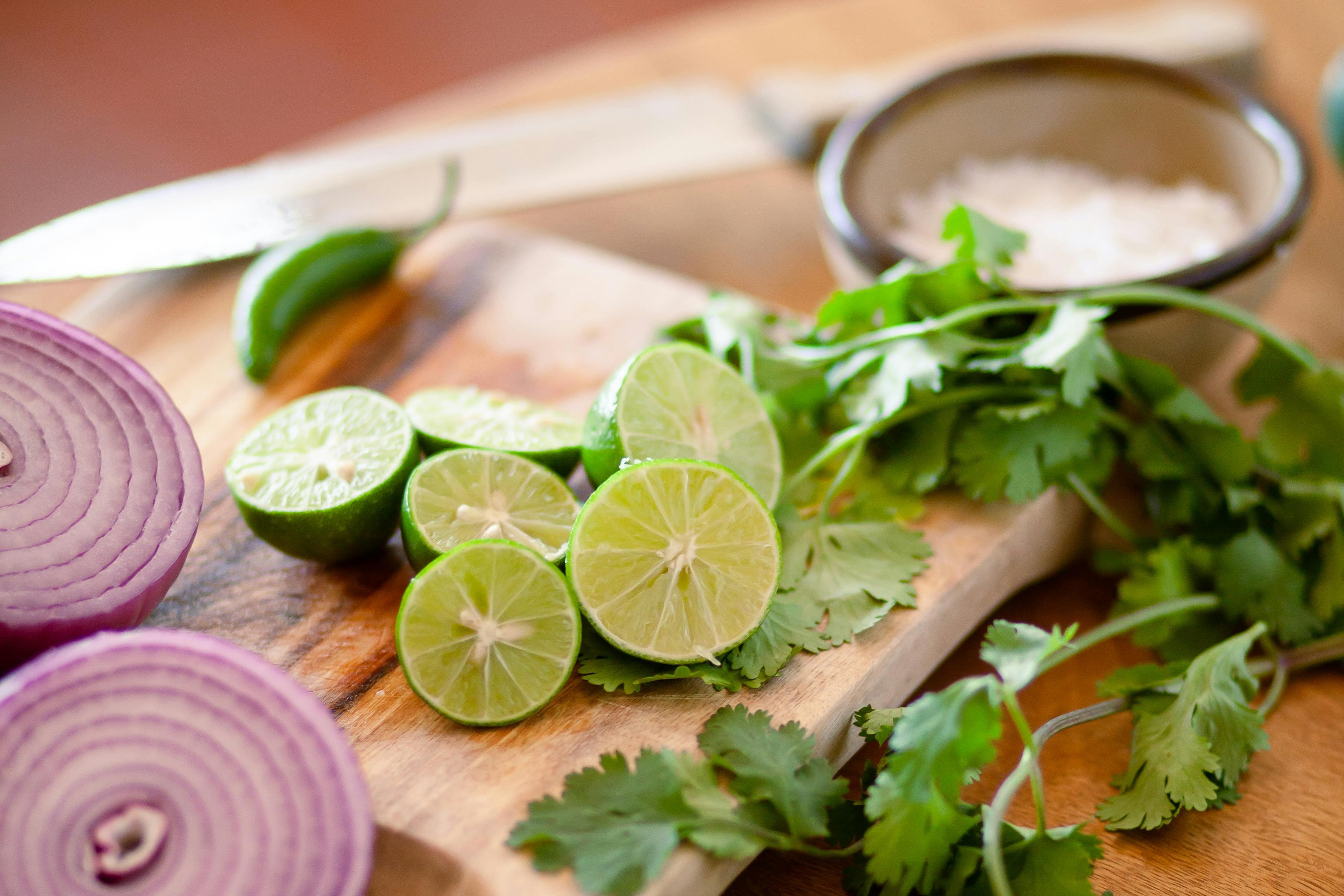 Fresh lemons and cilantro on a wooden cutting board.