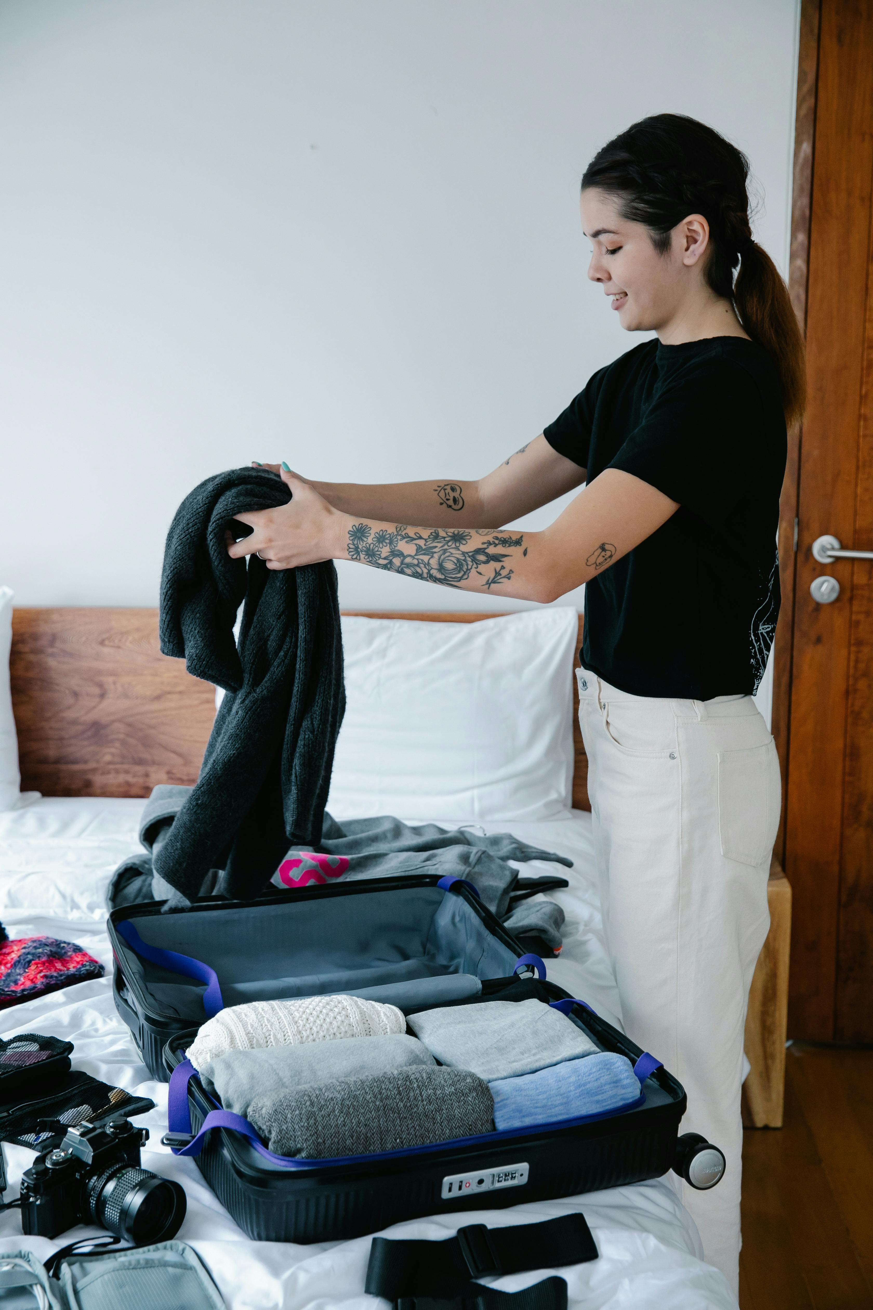 woman thoughtfully packing a suitcase with versatile clothing