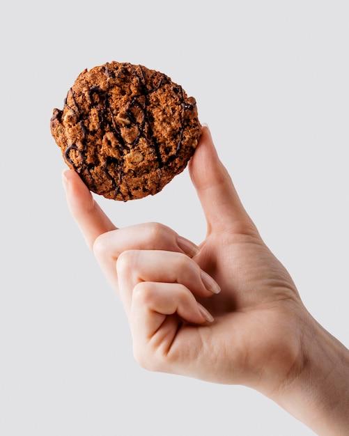 Close-up of a hand gently holding a freshly baked, unadorned butter cookie, ready for decorating