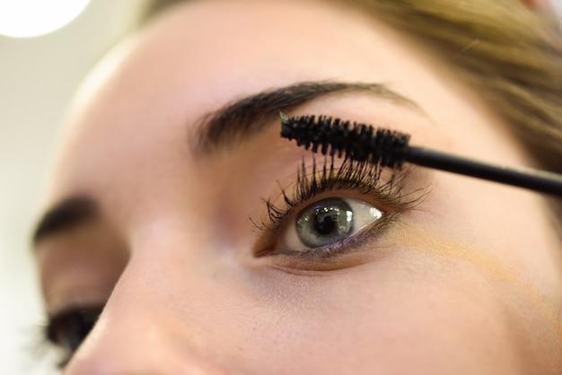 woman applying mascara to her eyelashes