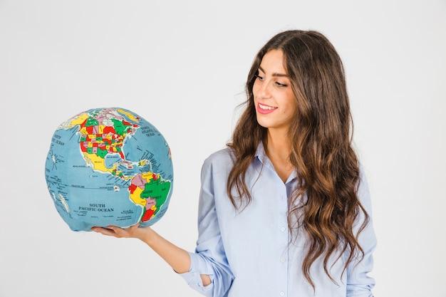 woman looking thoughtfully at a globe with a hand on her chin