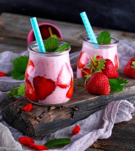 A refreshing Strawberry Lassi in a tall glass, garnished with fresh strawberries and mint leaves, with a backdrop of a bright, sunny kitchen
