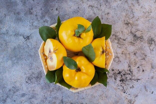 Whole and halved quinces on a wooden surface