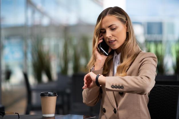 woman looking at clock while on phone