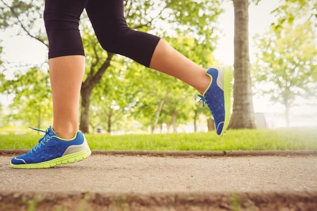 woman running in a park wearing running shoes