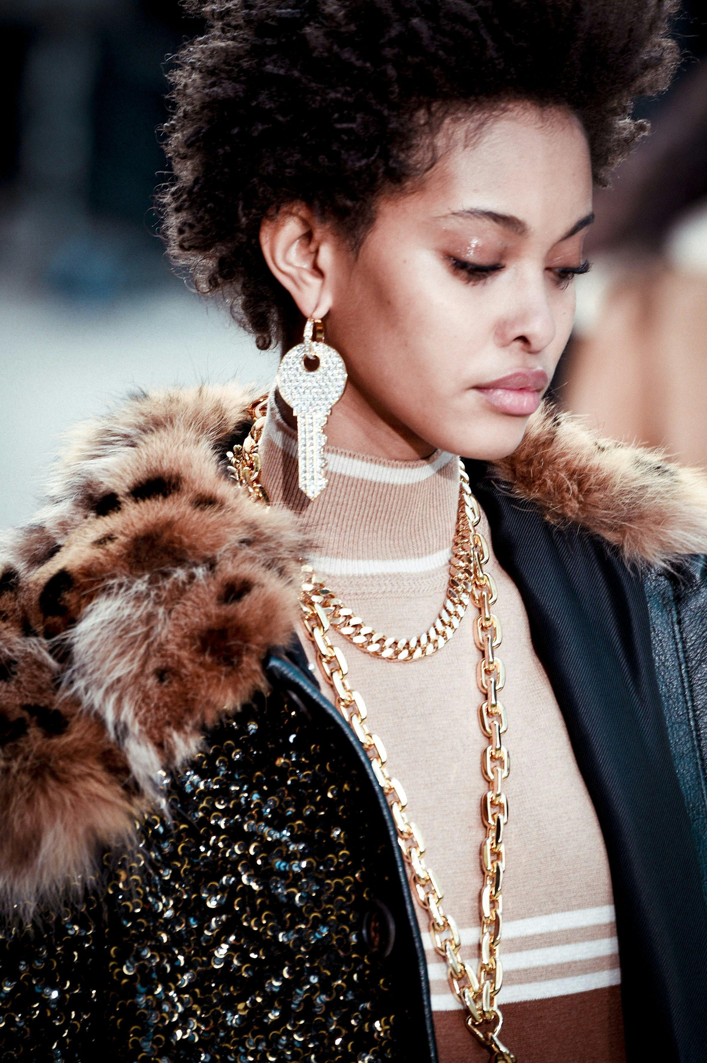 woman wearing chunky chain earrings at art gallery opening