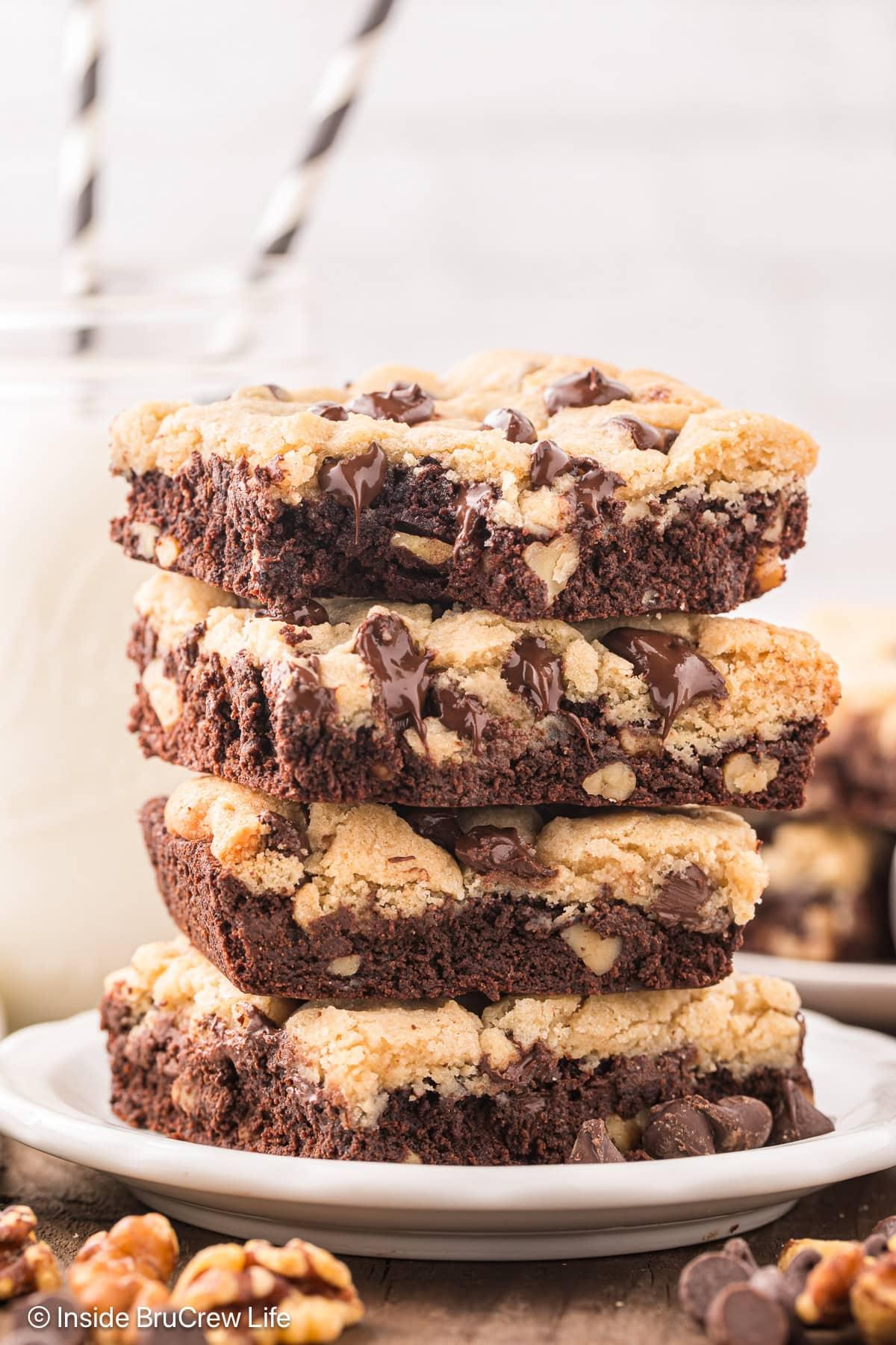 stack of chocolate brownie cookie bars on a white plate with melted chocolate drizzle
