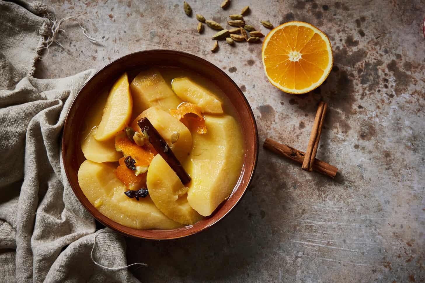 Quinces simmering in a saucepan with cinnamon sticks and lemon