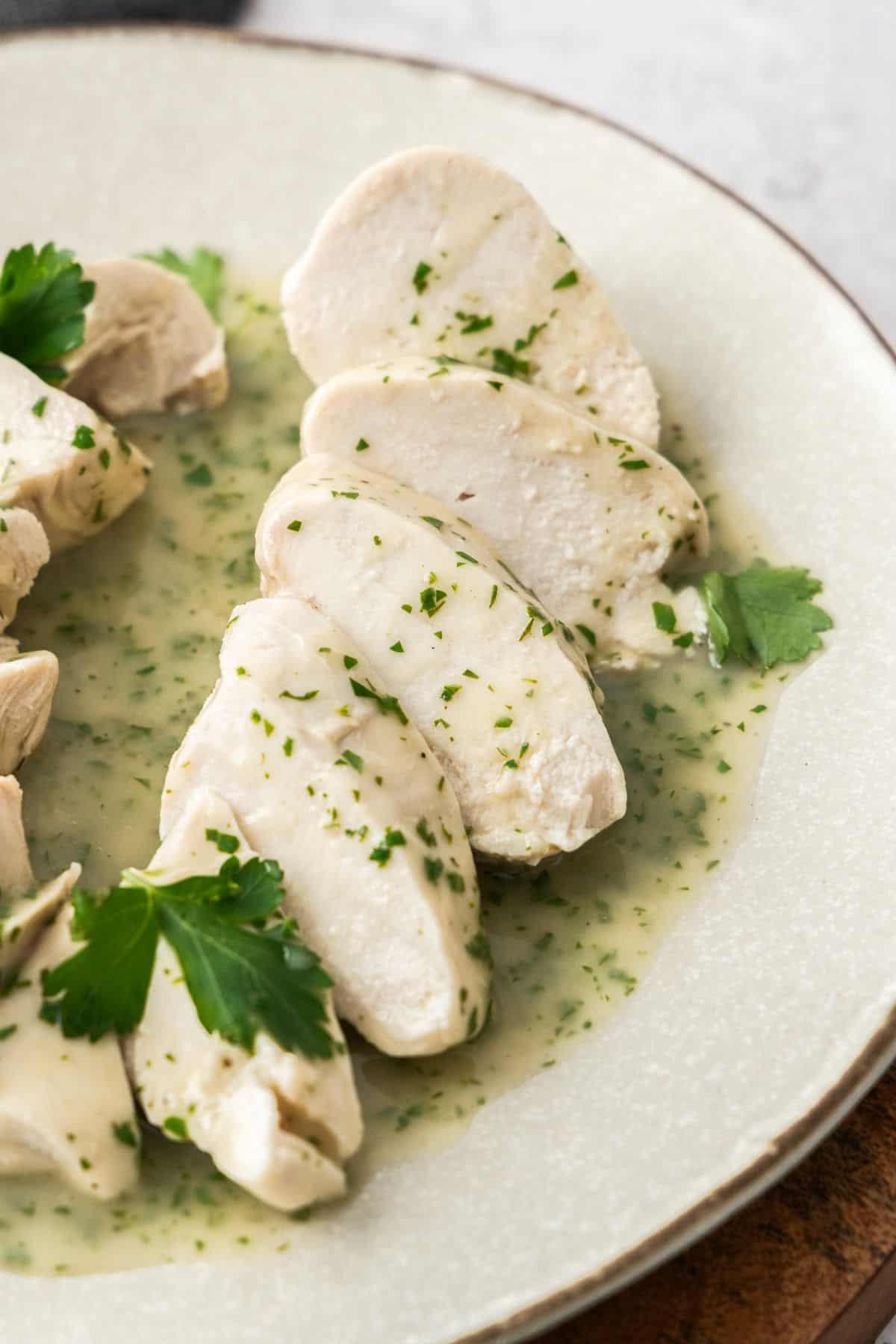 Creamy chicken breast slices served on a white plate with fresh parsley garnish, elegant presentation