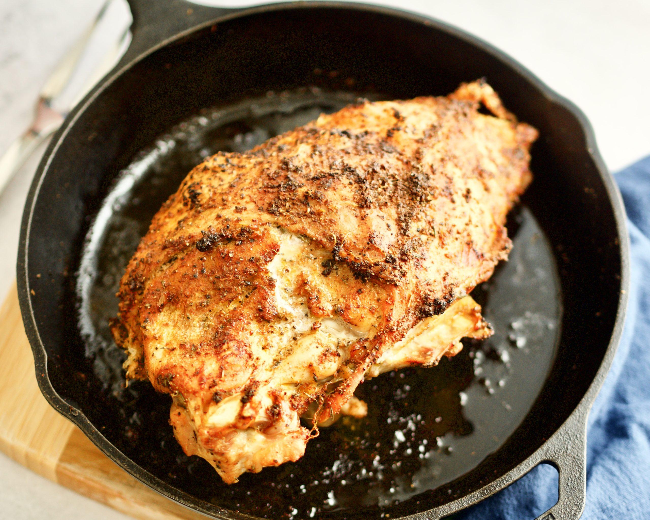 Close-up of a perfectly seared turkey breast in a cast iron skillet, golden brown crust visible