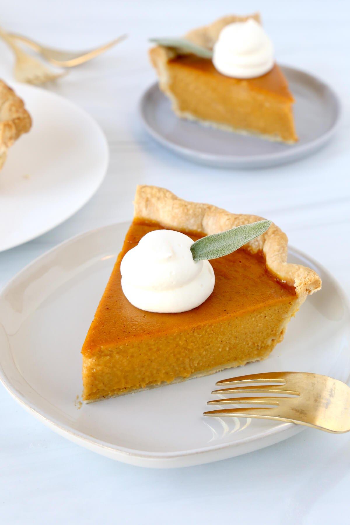 a close-up shot of a perfect slice of pumpkin pie on a white plate, dollop of whipped cream, fork ready
