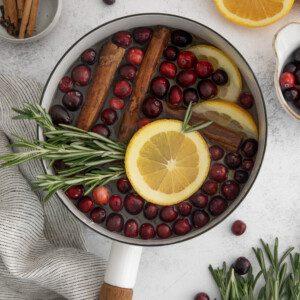 fresh cranberries, orange slices, and cinnamon sticks on a wooden cutting board