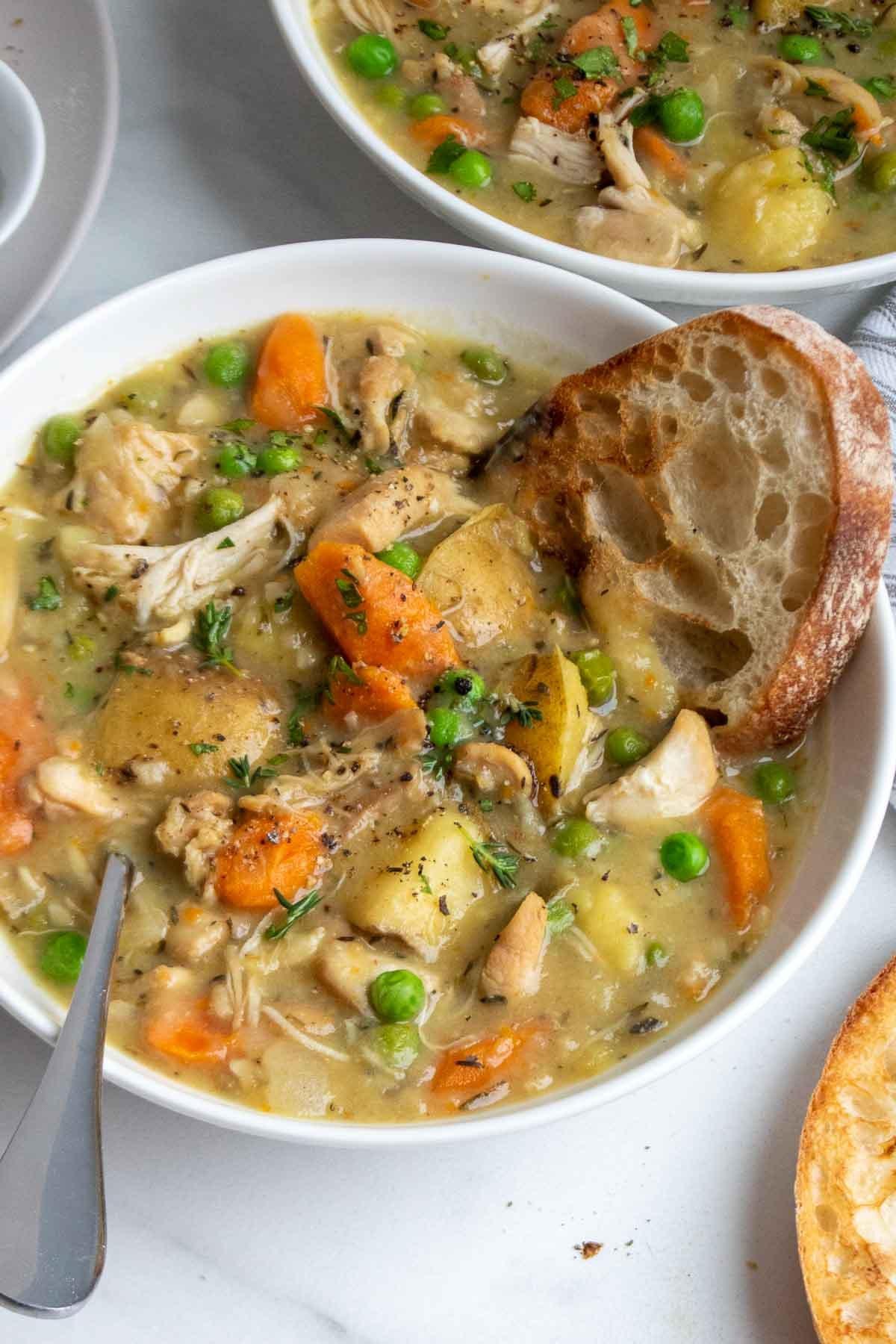 a bowl of slow cooker chicken stew with vegetables and crusty bread