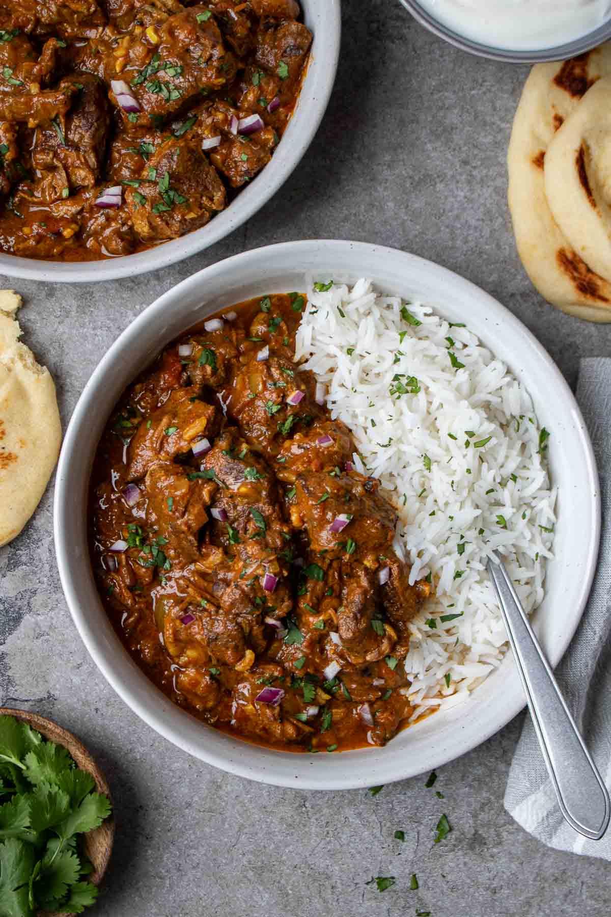chili masala beef stew served with basmati rice and naan with fresh cilantro