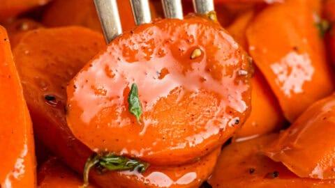 Close-up of a happy family sharing a Thanksgiving meal, with a side of glazed carrots prominently featured