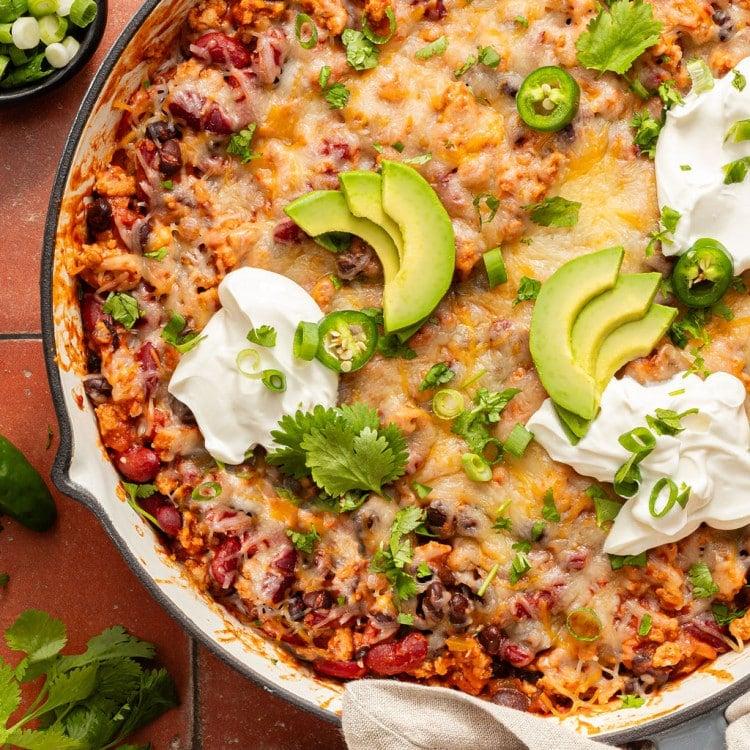 overhead shot of a full ground beef taco skillet ready to serve, with optional toppings on the side