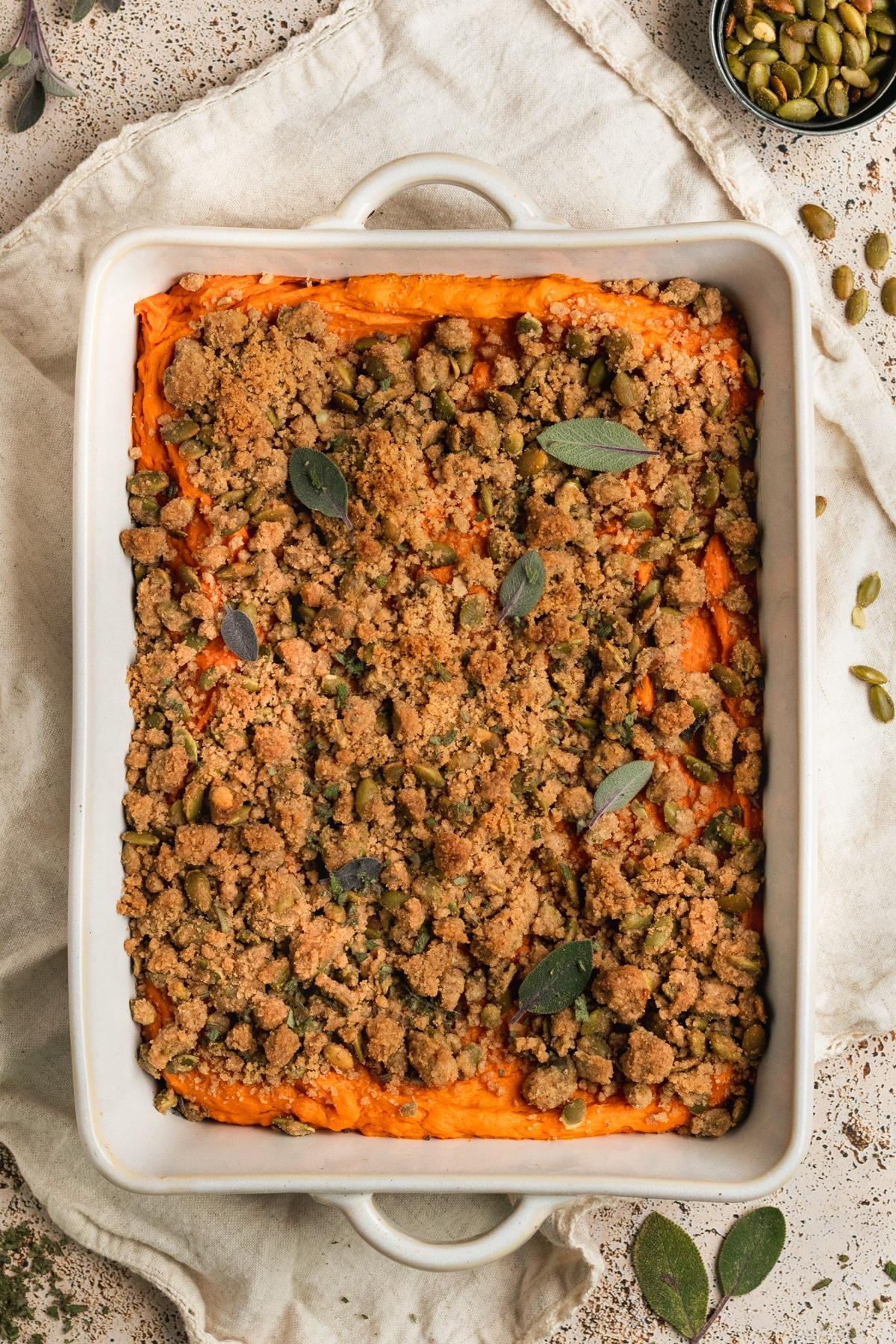 Overhead shot of a full roasted sweet potato casserole dish, the golden crust perfectly browned, ready to be served, on a white serving platter.