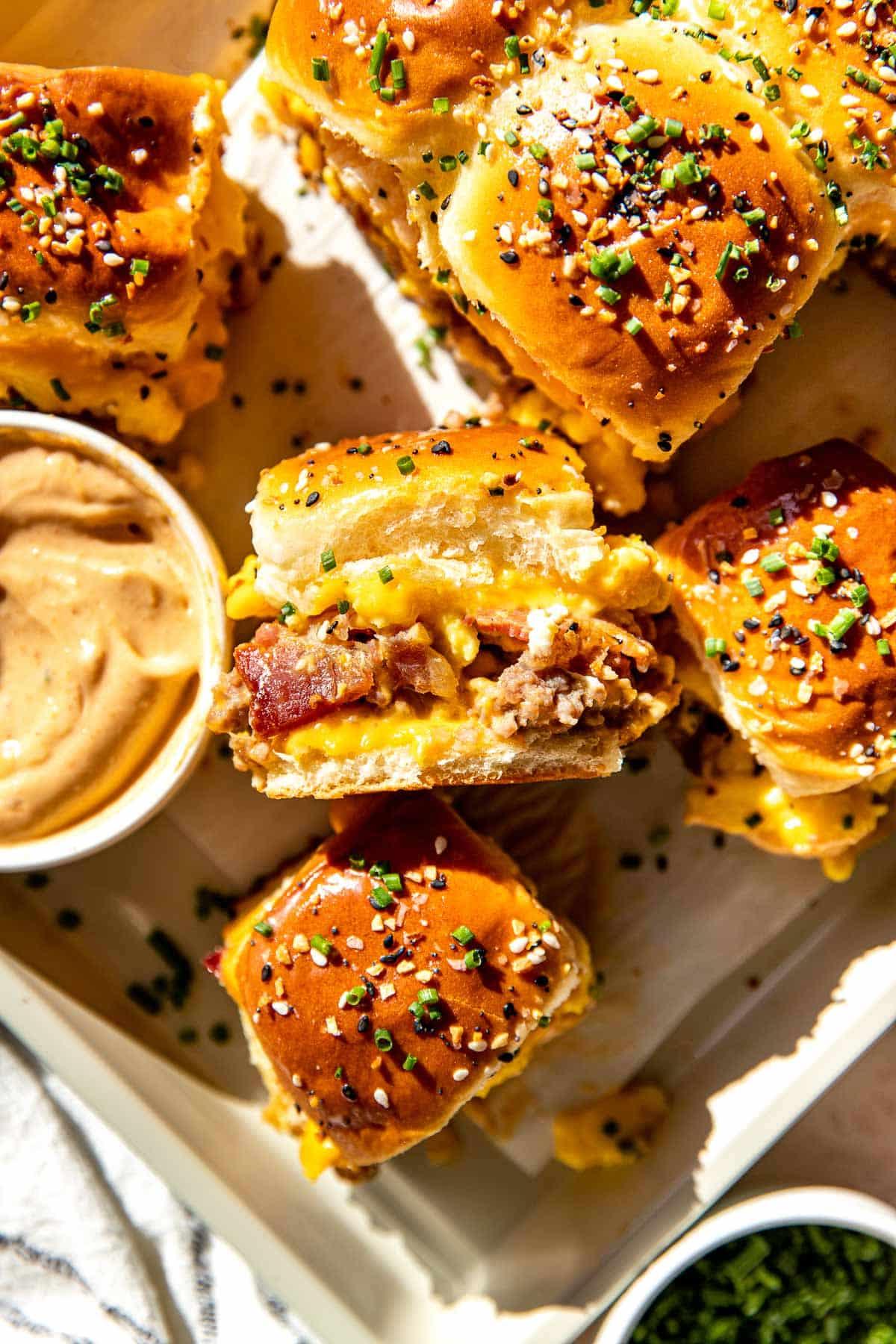 Rustic breakfast sliders with crispy bacon, fluffy eggs, melted cheddar cheese on toasted Hawaiian rolls, served on a wooden board