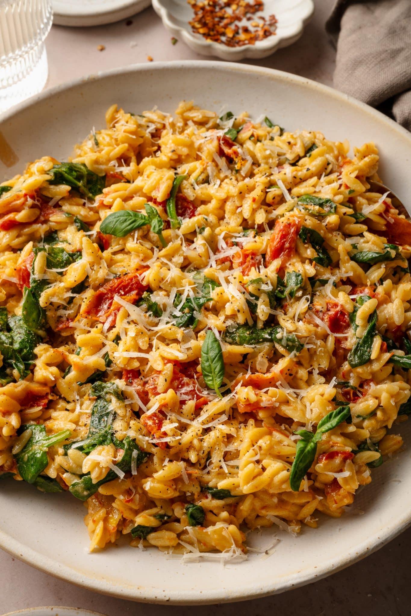 Delicious creamy Tuscan chicken orzo pasta dish with sun-dried tomatoes and spinach, rustic setting