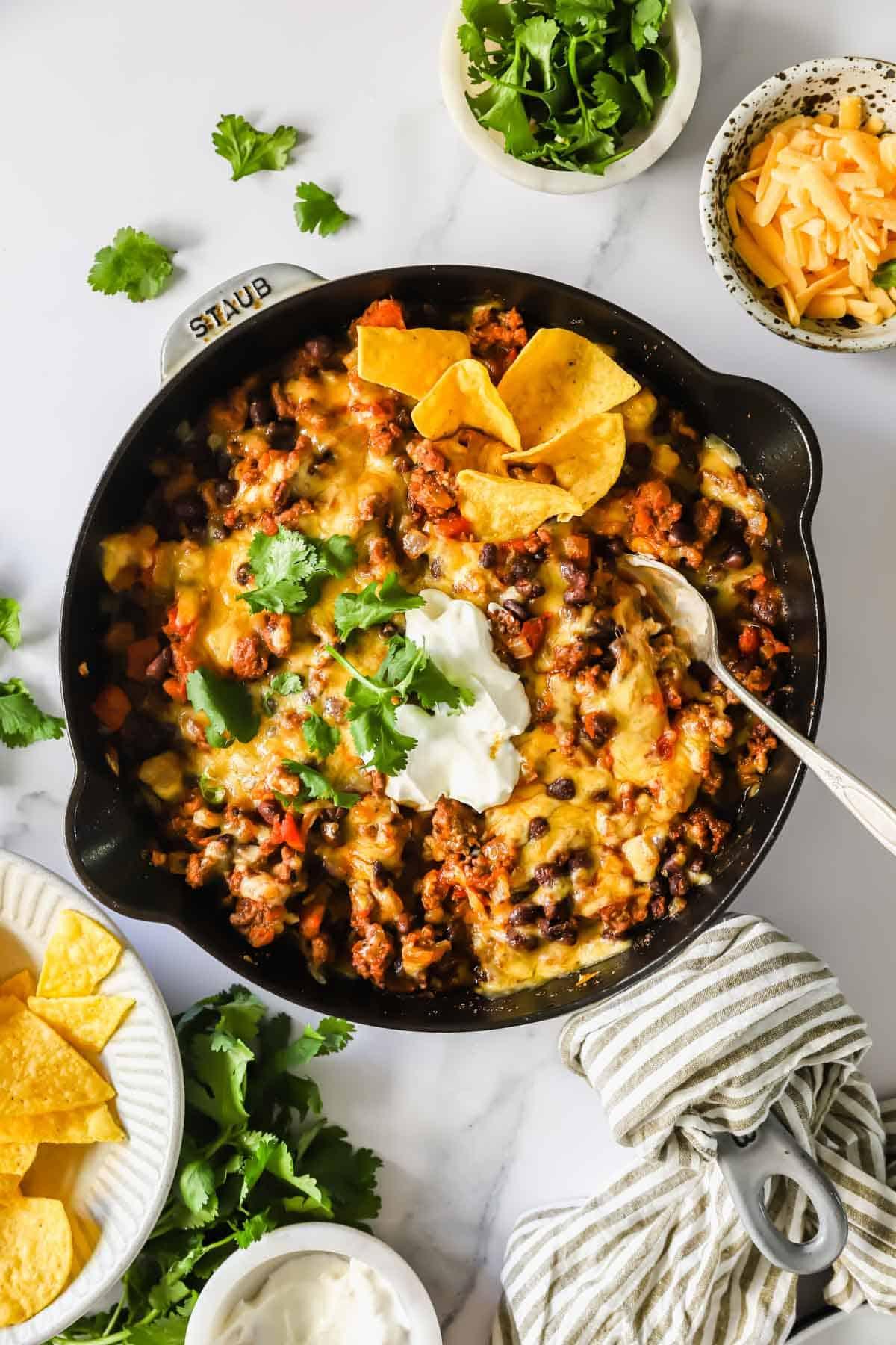 close-up of cooked ground beef taco skillet with cheese bubbling, garnished with cilantro