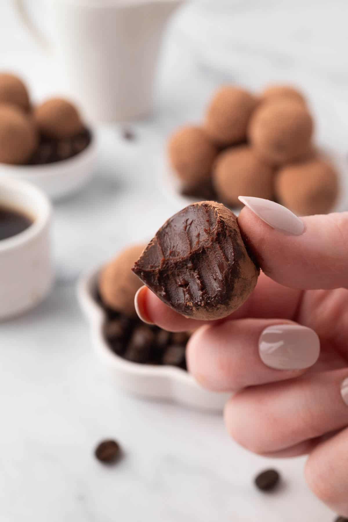 Overhead shot of a hand reaching for an espresso truffle from a small platter.