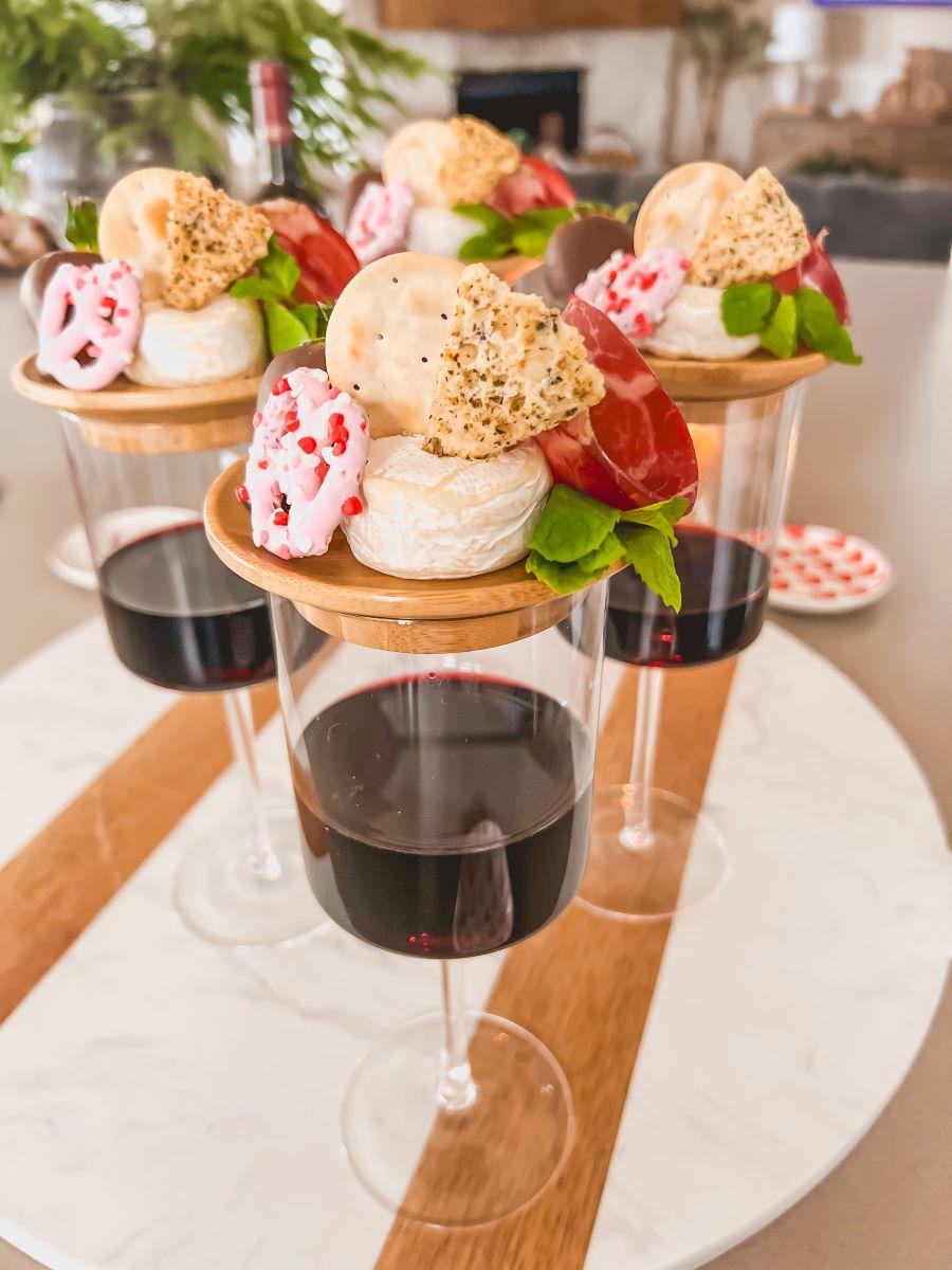 Assorted mini cheese tarts arranged on a serving platter with a glass of wine