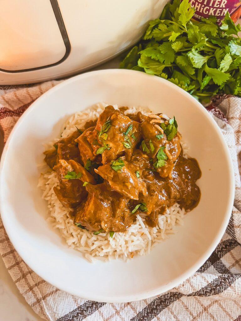 Close-up of tender chicken pieces simmering in a rich butter chicken sauce in a slow cooker