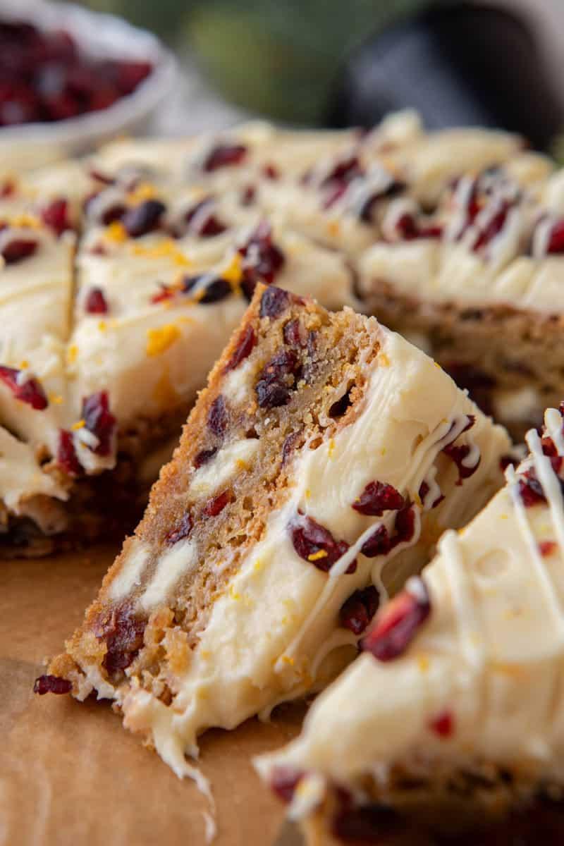 slice of cranberry bliss bar showing the chewy base, cranberries, and thick cream cheese frosting