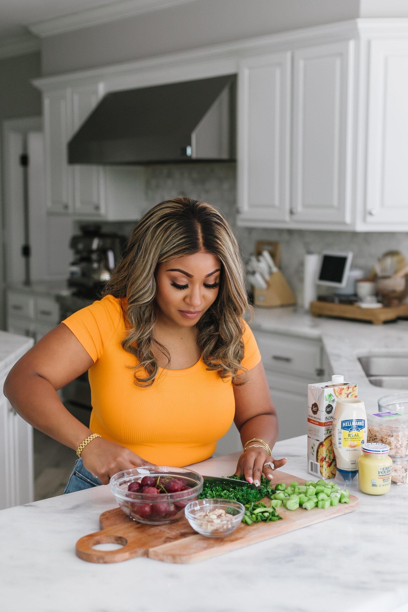 Smiling woman enjoying a vibrant chicken salad bowl in a sunny kitchen