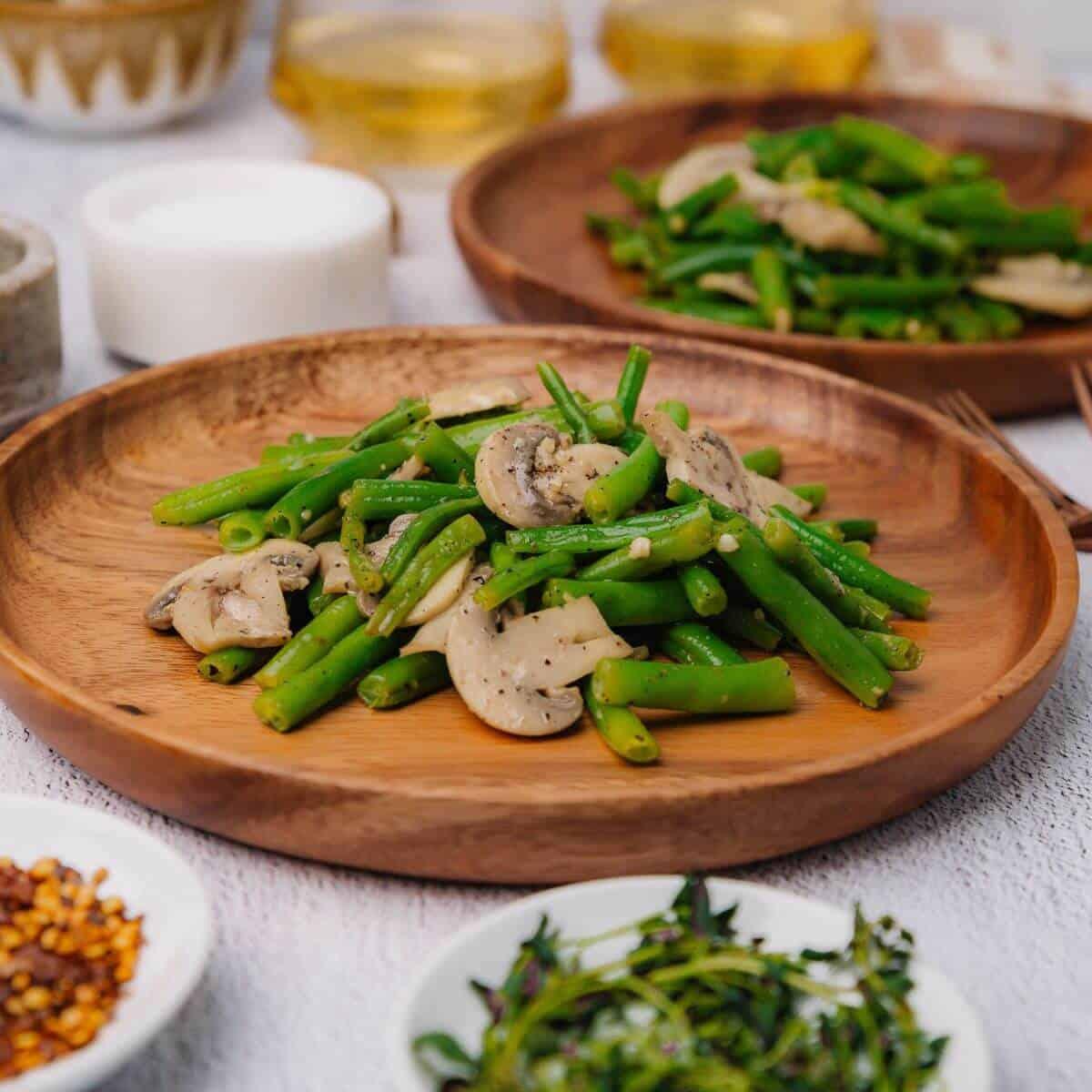 fresh green beans and sliced mushrooms on a wooden cutting board