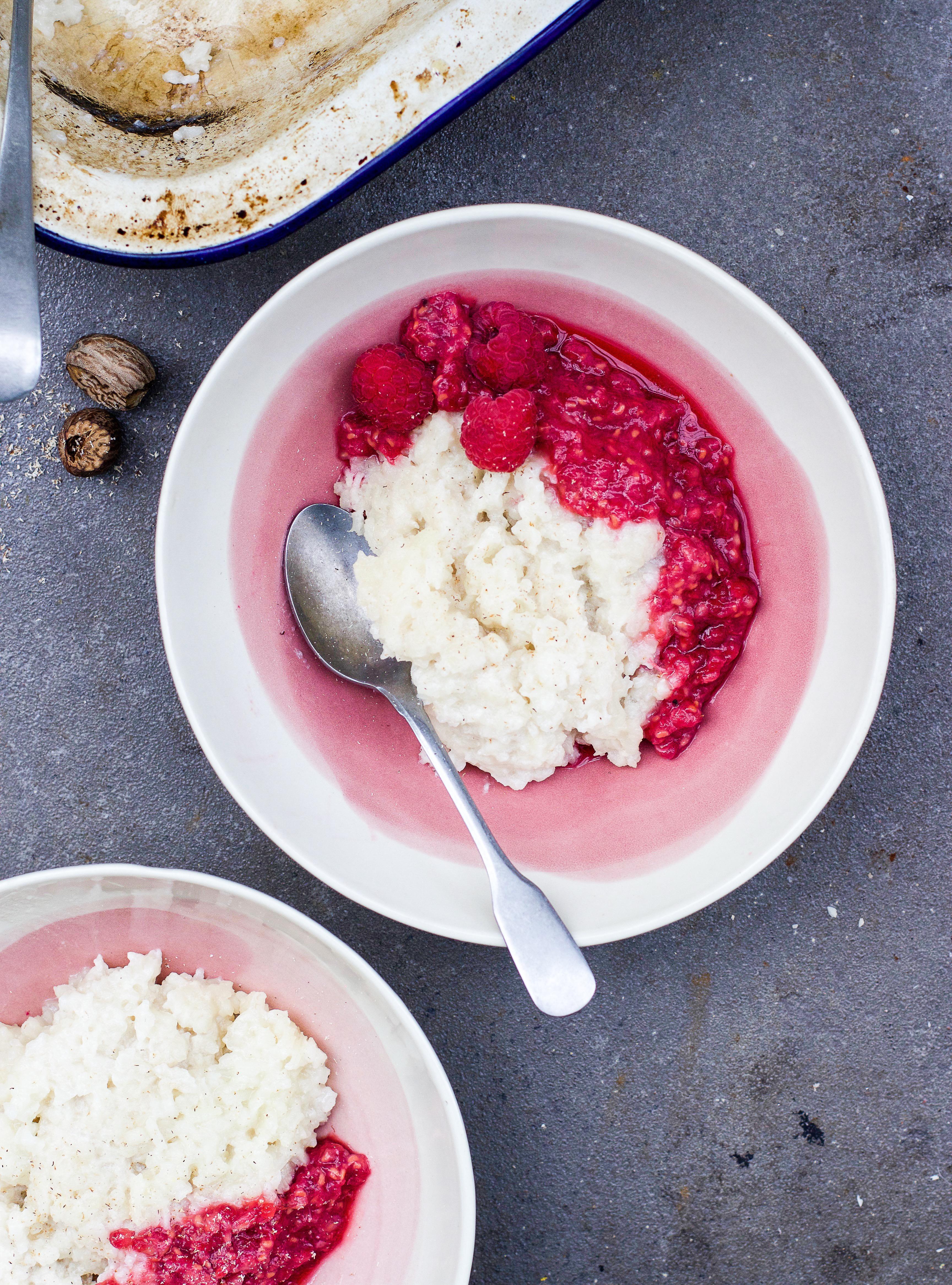 Close-up shot of a spoonful of rice raspberry rose pudding being lifted from a bowl, showcasing its creamy texture and raspberry swirls.