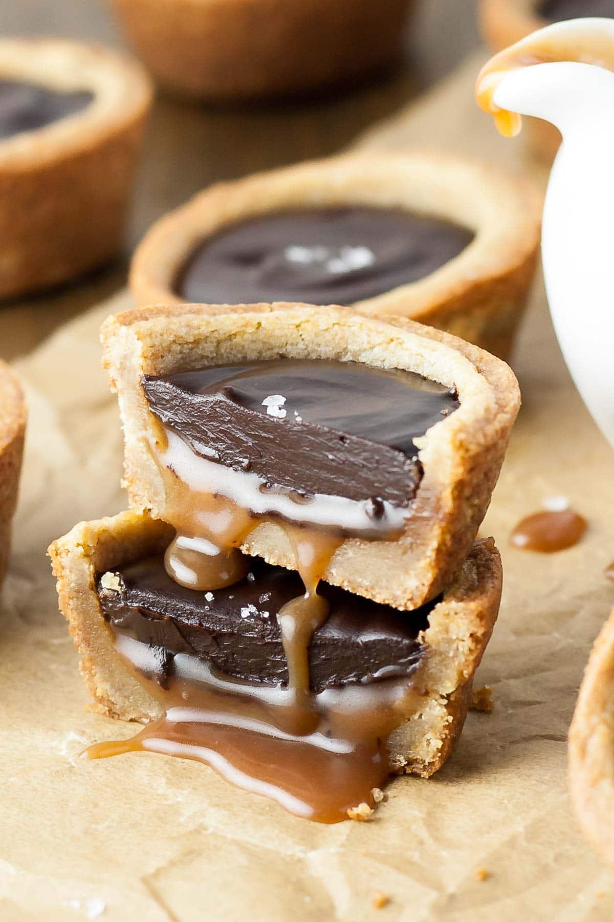 Close-up of gooey caramel being poured into chocolate cookie cups, with a spoon dripping caramel