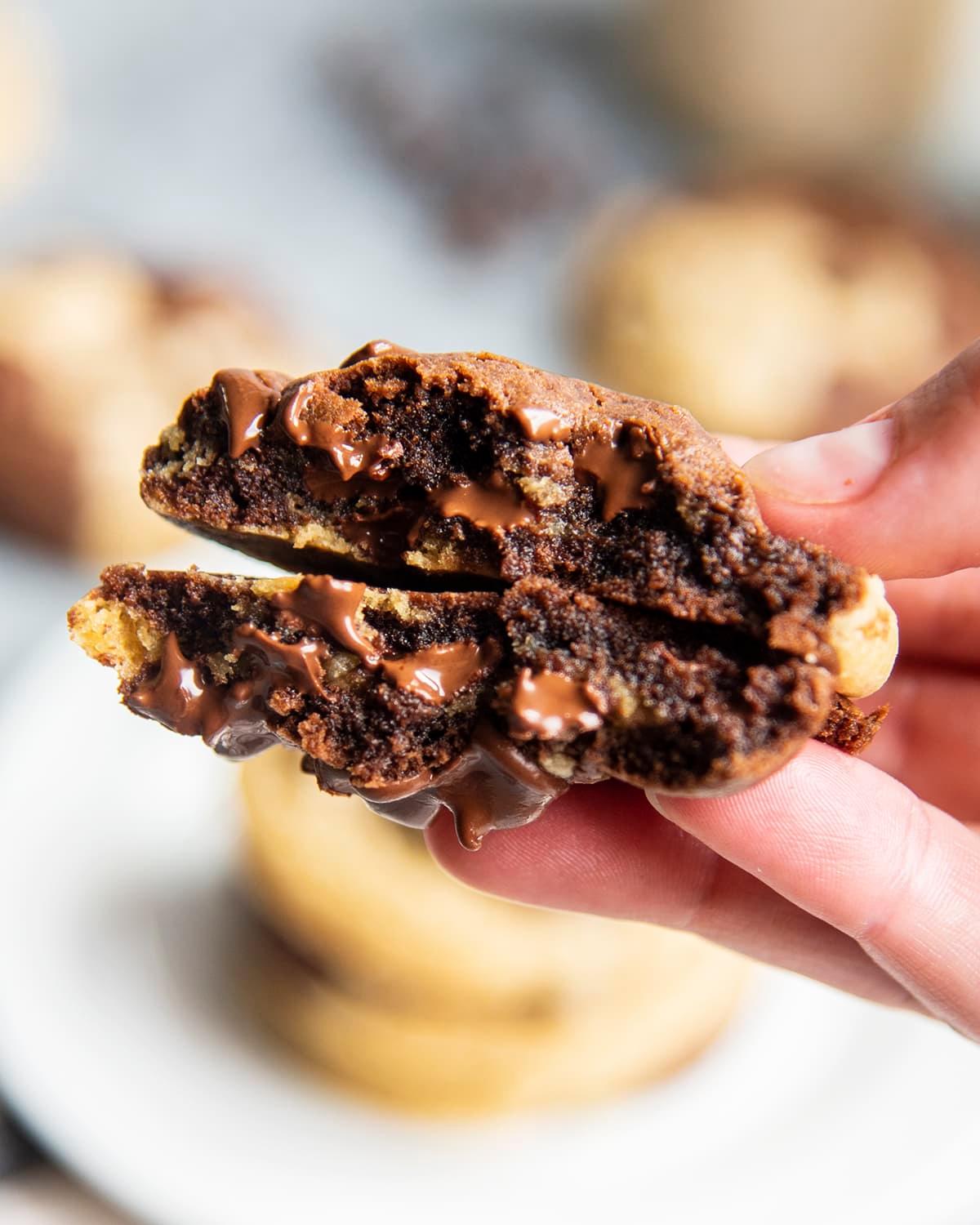 Child's hand reaching for a warm, chewy chocolate marble cookie from a plate