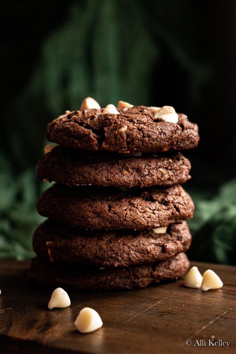 Close-up shot of a stack of cocoa cookies with elegant white drizzle on a rustic wooden board