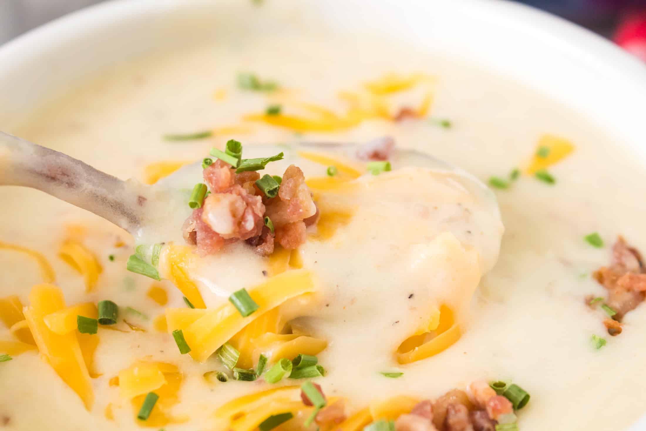 Close-up of creamy cheddar potato soup simmering in a Dutch oven, steam rising