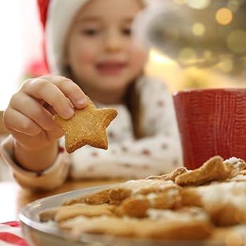 Happy child with flour on their nose, holding a star-shaped cookie cutter in a kitchen