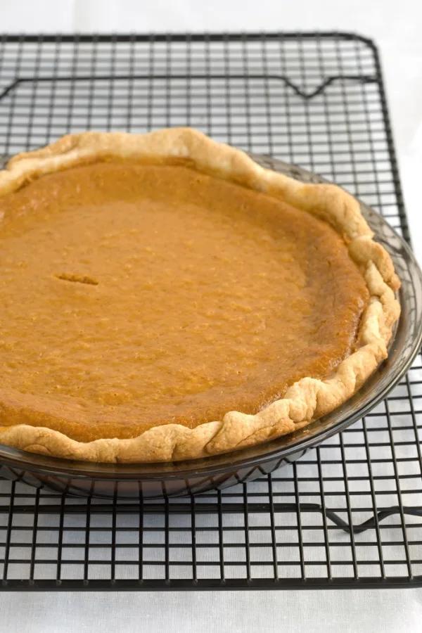 overhead shot of a whole silky pumpkin pie on a cooling rack