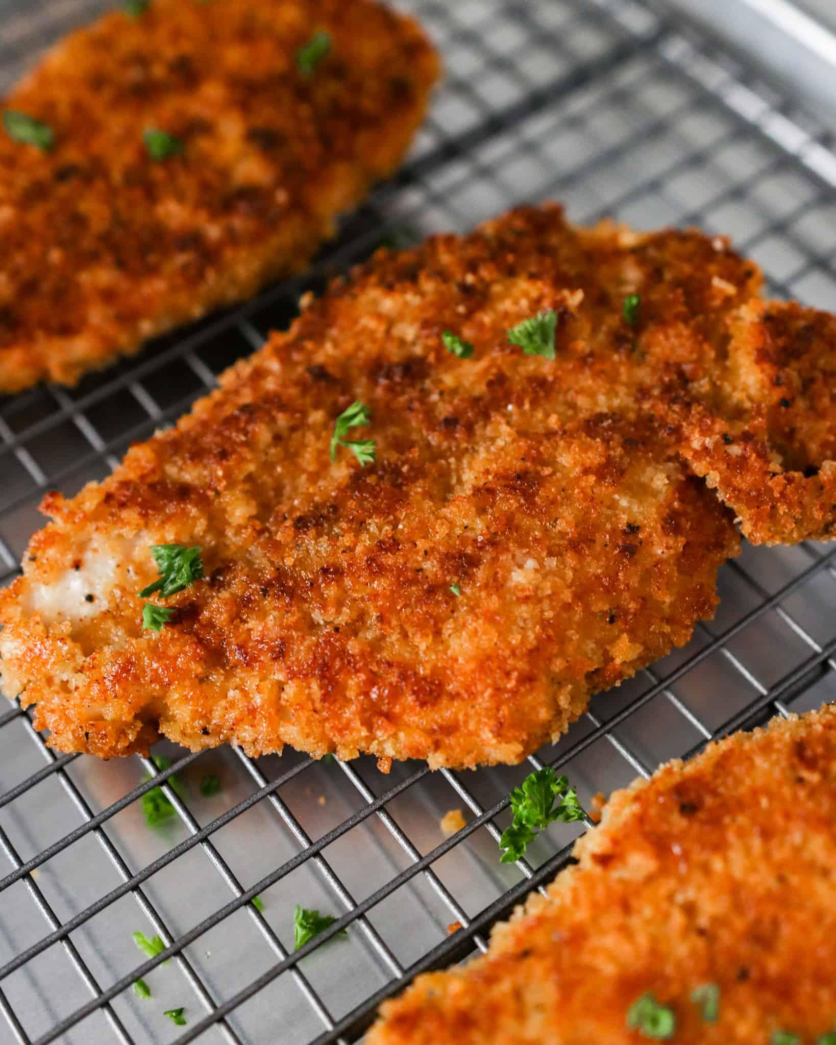 Hands breading chicken cutlets with parmesan and panko